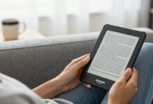 Pessoa relaxando em um ambiente aconchegante enquanto lê em um Amazon Kindle, com café ao lado e luz natural, transmitindo conforto e modernidade na leitura digital.