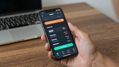 Usuário segurando smartphone com aplicativos de comparação de preços abertos, mostrando gráficos e etiquetas de desconto