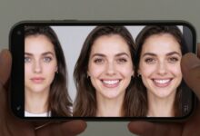 Uma mulher sorrindo segura um smartphone exibindo uma foto sendo editada com o aplicativo Facetune, mostrando a interface de retoque facial.