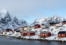 Uma paisagem ártica de Longyearbyen, com suas casas coloridas contrastando com as montanhas nevadas e o céu azul, evocando o mistério da vila que proibiu a morte.