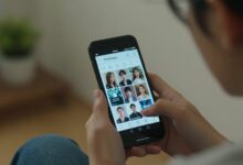 Uma pessoa assistindo a um drama asiático em um smartphone com o logo do aplicativo PineDrama em destaque, em um ambiente aconchegante.