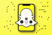 Um smartphone exibindo a interface do Snapchat com vários ícones de recursos, como Lentes de Realidade Aumentada e o Mapa de Snaps, sobre um fundo amarelo vibrante característico da marca.