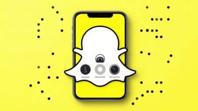 Um smartphone exibindo a interface do Snapchat com vários ícones de recursos, como Lentes de Realidade Aumentada e o Mapa de Snaps, sobre um fundo amarelo vibrante característico da marca.