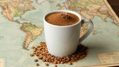 Uma xícara de café fumegante sobre grãos de café torrados, com um mapa antigo ao fundo, simbolizando a jornada histórica da bebida pelo mundo.