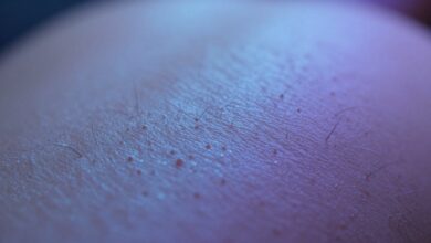 Close-up macro shot of human skin with goosebumps, showing the hairs standing on end, with a soft, ethereal blue and purple light.