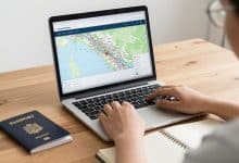 Viajante planejando uma viagem econômica com laptop aberto em uma busca de voos, mapa de destinos, caderno de anotações e passaporte sobre uma mesa iluminada.