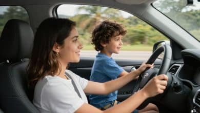 Motorista e passageira viajando em um carro moderno por uma estrada brasileira, com malas, paisagem ensolarada e atmosfera de segurança e confiança